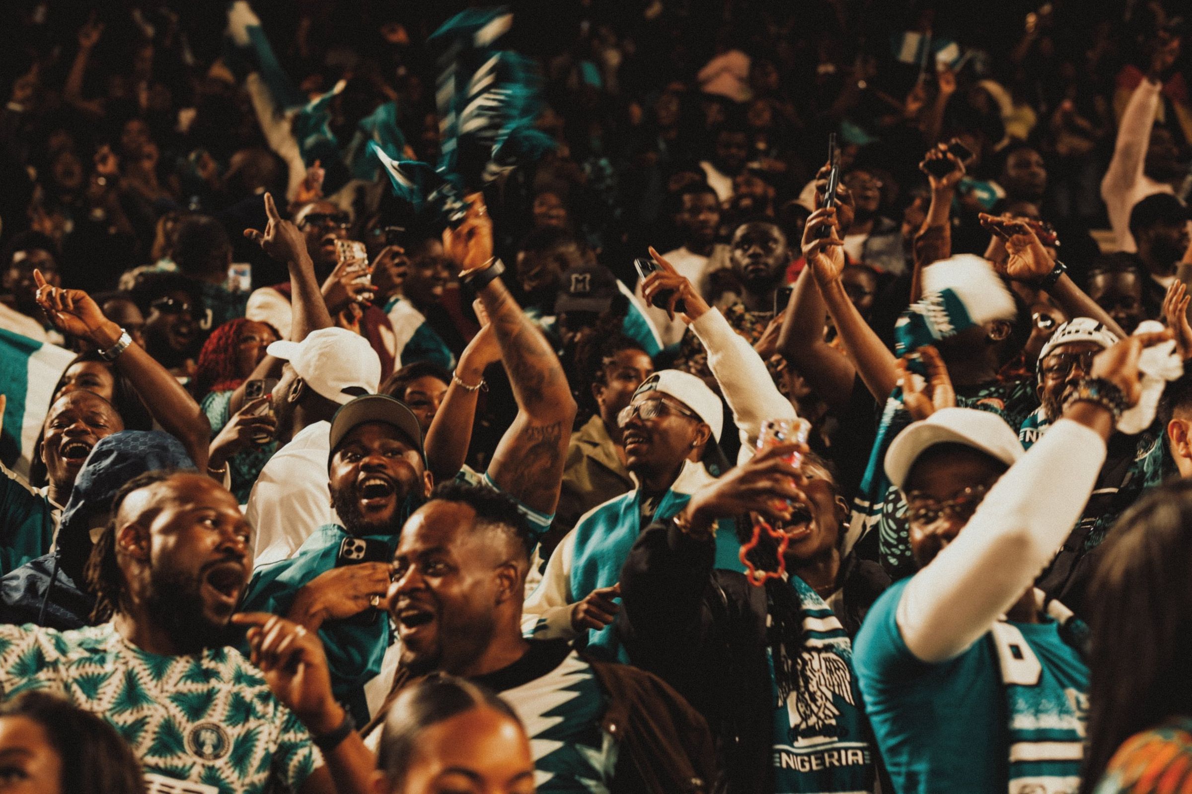Nigeria supporters on their feet in the stands, waving flags and singing